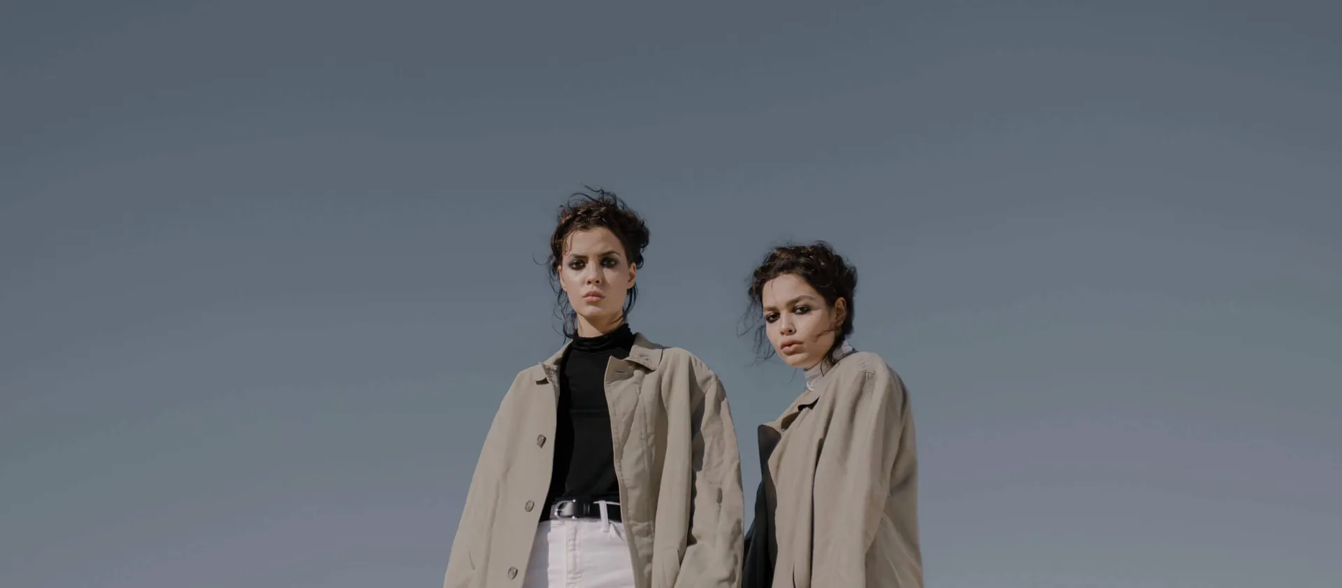 Two models wearing oversized beige coats